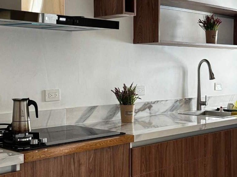 Cocina con gabinetes de madera, tope de mármol y campana de acero
