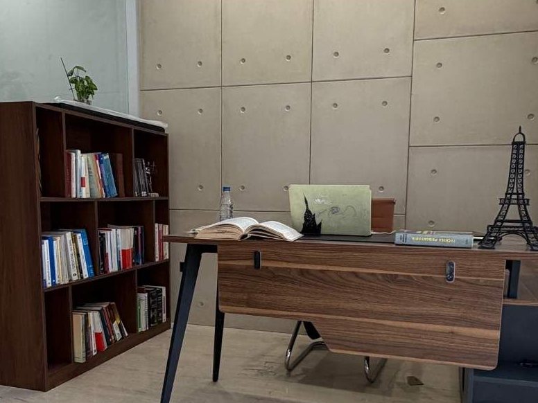 Oficina con escritorio y biblioteca de madera frente a una pared de paneles de concreto